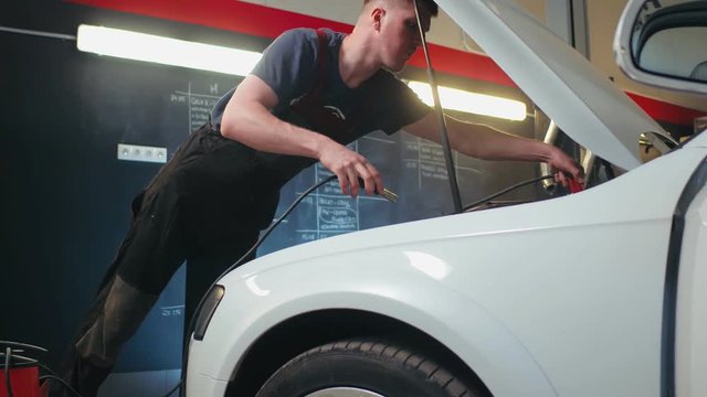 Auto service worker checking voltage on car battery. Car service station