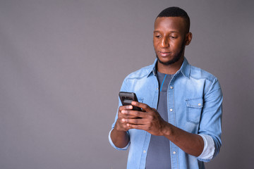 Young handsome African man with short hair against gray backgrou