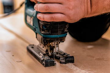 Close up of working with an electric jigsaw up a tree.
