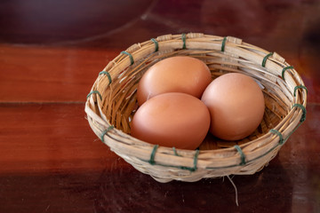 Eggs in bamboo basket on a wooden table.