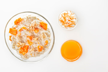 Oatmeal with pumpkin and nuts, salad and a glass of fresh juice on a white background. Top view Copy space.