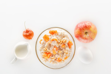 Oatmeal with pumpkin and nuts, salad, egg and a jug of milk on a white background. Top view. Copy space.