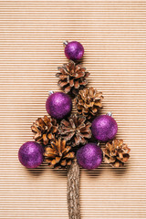 Flat lay of purple christmas balls and pine cones in the form of Christmas tree on the textured background