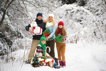 Happy family with christmas gifts in winter forest