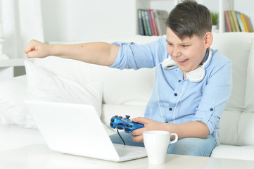 Portrait of boy playing computer game with laptop