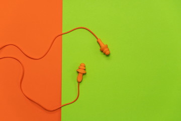 orange earplugs for protect noise from loud environment pollution on colorful green background