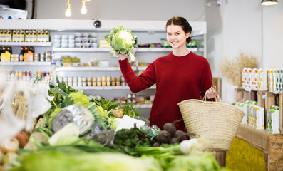 Fototapeta premium cheerful young girl buying cauliflower at market