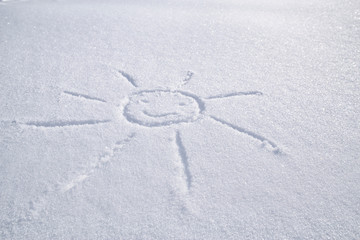 Smiling sun drawn on white snow on a frosty winter day.