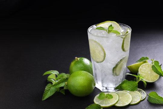 Fresh lime soda in glass drink with sliced lime on black background