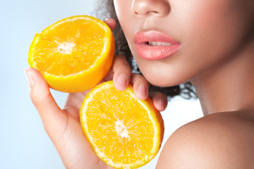 Young beautiful black girl with clean perfect skin with lemon close-up