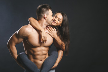Sporty young happy sexy couple isolated over black background.