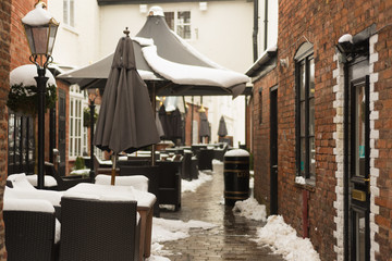 tyical English street scene after snow fall with tables and chairs and parasols