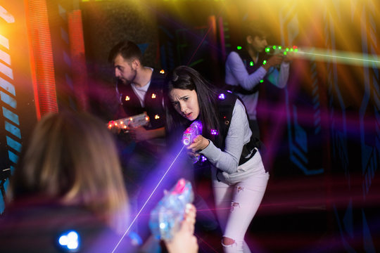 Girl playing laser tag in colorful beams