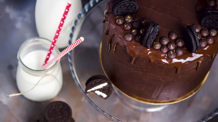 Chocolate cake decorated with biscuits next to jars of milk with tubules and broken biscuits. Banner image Top view