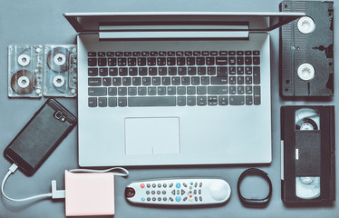 Modern digital gadgets, storage media, devaysy and obsolete analog media devices on a gray paper...