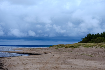 dirty beach by the sea with storm clouds above