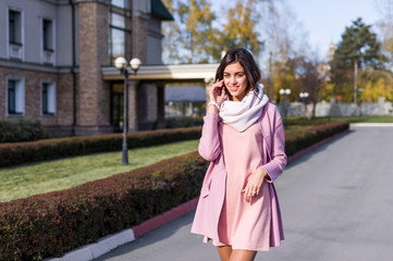 portrait of a young beautiful brunette woman on the street, autumn afternoon in warm seasonal clothes, women's urban street fashion, warm colors