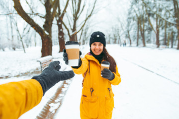 Fototapeta na wymiar woman give cup of coffee to friend. meeting in snowed winter park