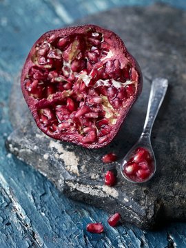 Half a pomegranate with a spoonful of seeds next to it