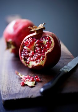 A pomegranate which has been broken open on a wooden board
