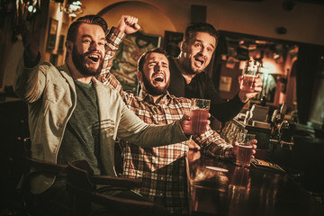 Old friends having fun and drinking draft beer at bar counter in pub. - obrazy, fototapety, plakaty