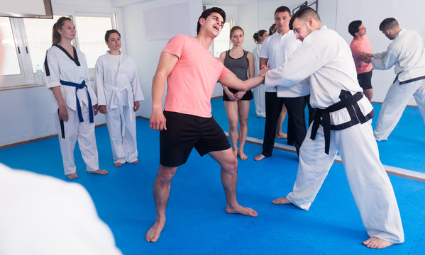 man training new taekwondo holds with adults during class