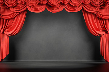 Theater stage with red velvet curtains and chalkboard coating for text.