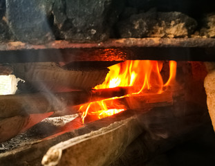Fire inside a traditional oven with burning wood logs and smoke