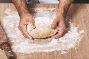 male chef kneads the dough