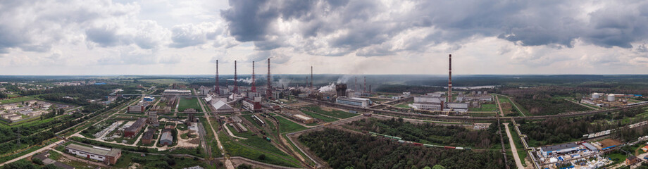 Fototapeta na wymiar Industrial landscape. Panoramic view of the technological pipe and industrial infrastructure. Chemical production with red-white pipes and smoke is coming. Production buildings.