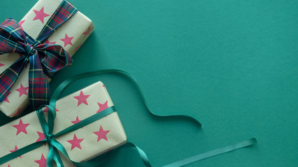 Christmas gift box wrapped in ornament paper on green background . Top view.