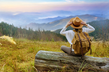 Woman traveler with backpack enjoying sunset on peak of mountain. Concept of travel.