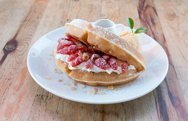 Close up of vanilla ice cream with waffle and fresh strawberry on wood table background
