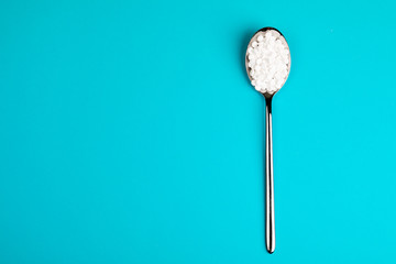 Sugar substitute pills in a spoon, on a blue background