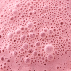 Macro photo of berry healthy pink smoothie with bubbles. Food background. Tip view