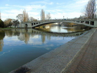 View of Reading Bridge, over the River Thames looking downstream, with reflections of the trees and bridge.