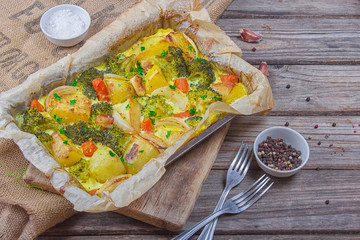 Broccoli carrots, potatoes,white onion and garlic with cheddar egg casserole in baking dish on wooden background. Top view, copy space