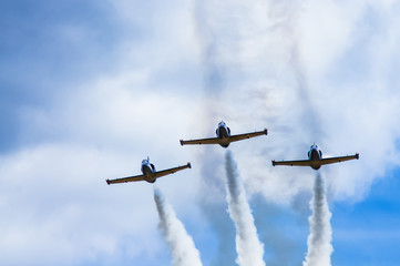 Three jet combat training aircraft leave a smoke trail against the sky.