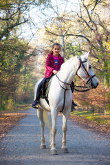 Obraz premium A girl rides a white horse in the forest