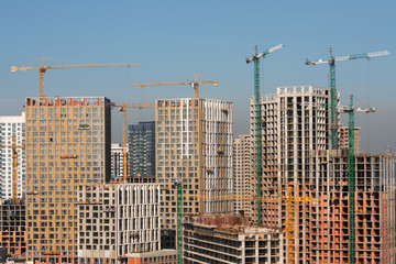 New high-riser buildings with cranes. Smog on background. Big city concept.