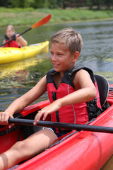 Obraz premium background. handsome guy sits in a kayak in a red life jacket and holds a paddle