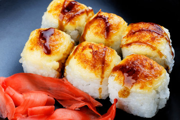 Baked sushi on a black background. Appetizing sushi closeup.