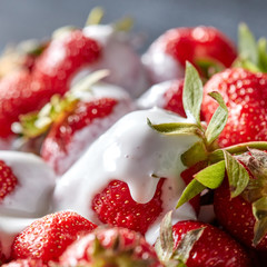 Closeup of juicy organic strawberries with green leaves and fresh cream. Healthy dessert