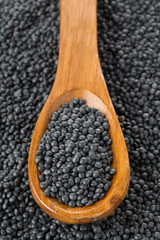 Heap of black organic beluga lentils in wooden spoon on black beluga lentils
