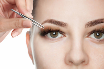 Makeup artist plucks the eyebrows of a beautiful woman in the beauty salon. Face close up. Professional care for face.