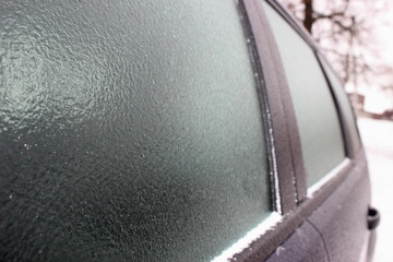 Car with frosted frost-covered windows in winter - driving safety, ice heating, preparation for the trip, front-side view close up