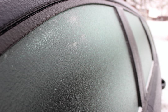 Car with frosted frost-covered window in winter - driving safety, heating, preparation for the trip, front-side close up view