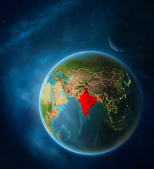 Planet Earth with highlighted India in space with Moon and Milky Way. Visible city lights and country borders.