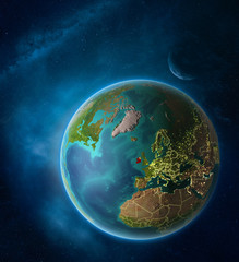 Planet Earth with highlighted Ireland in space with Moon and Milky Way. Visible city lights and country borders.