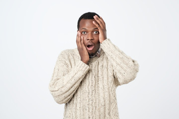 Puzzled or suprised african man dressed in sweater looking in shock and frustration